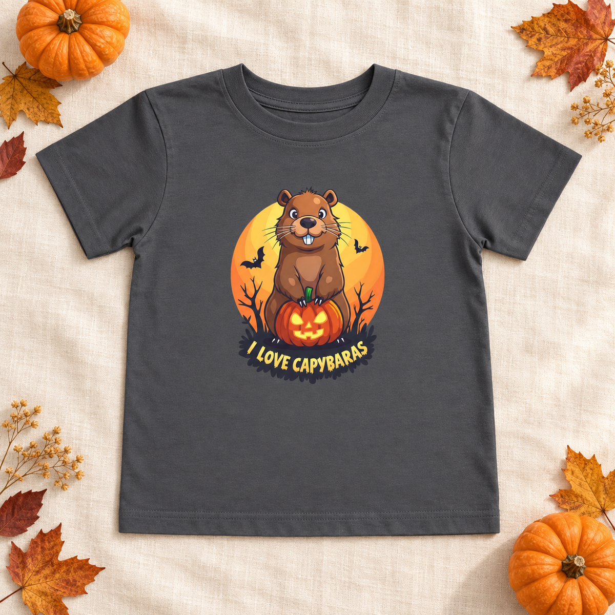 AI-created flat lay: Asphalt I Love Capybaras Halloween toddler tee with pumpkins and autumn leaves.