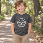 AI-created lifestyle mockup: Asphalt Capybara Club toddler tee on a nature walk.