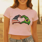 Person wearing a pink t-shirt with a heart design made of American and Brazilian flags, standing outdoors.