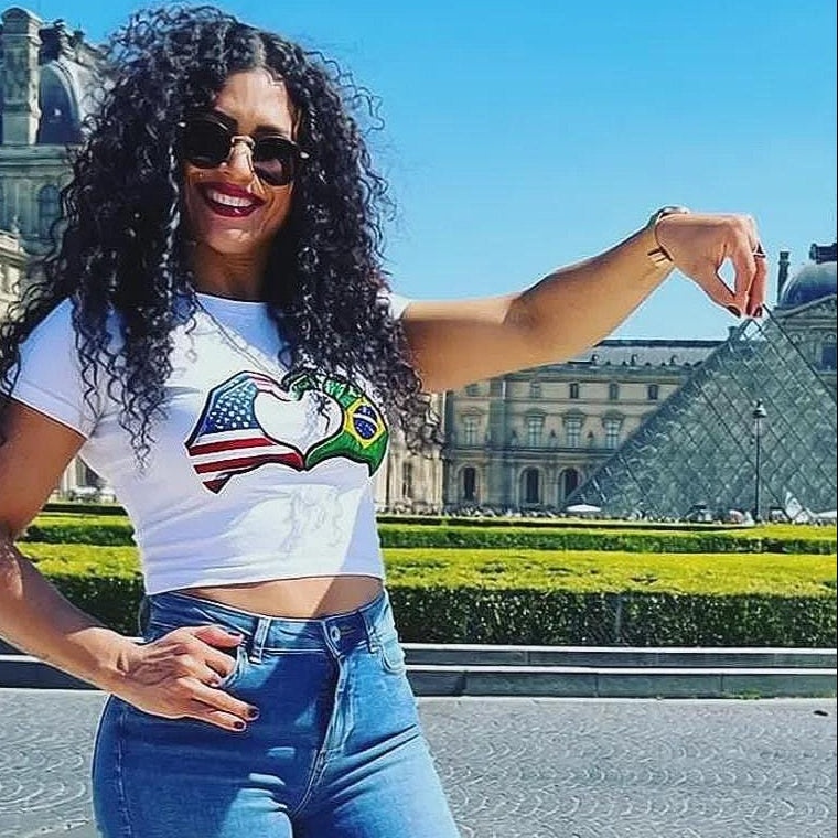 Woman wearing a white t-shirt with a colorful graphic design in front of a famous landmark.